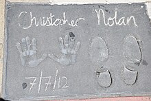A hand and footprint reading "Christopher Nolan" at the top and "7/7/2012" at the bottom.