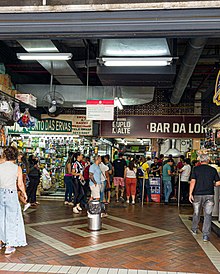 Entrada do Mercado Central de Belo Horizonte. Na foto, é possível ver algumas lojas e várias pessoas.