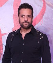 Fardeen Khan wearing a black shirt with sequins or other decorations on shoulders, looking right of camera