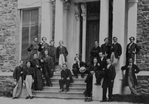 Un groupe d'hommes rassemblés sur le perron d'un immeuble, posés en tenue de soirée.