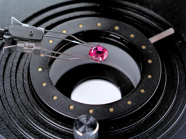 Examining a pink sapphire under a gemmological microscope