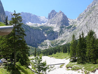 A view upstream from Höllentalangerhütte Deutsch: Talschluss mit Wasserfall, Riffelwandkamm und Riffelkar, Gebirgsbach und Holzsteg