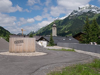 Back side of a hotel construction site in Lech, Vorarlberg, Austria. Views of landscape and church tower.