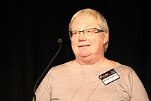 Brenda Chawner'ın Yeni Zelanda Açık Kaynak Ödülleri'nde jüri olarak rolünde siyah bir arka plana karşı bronz bir üstte portresi