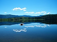 Lago blu con riva lontana visibile e un cielo limpido sopra il lago