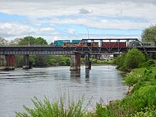 Class DL 9285 with a northbound freight on Ngaruawahia railway bridge with a Toll truck on the road bridge. Turangawaewae is in the background. Ngaruawahia rail and road bridges.jpg