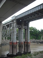 Brunel's cast iron pillars for the original bridge, still supporting the modern railway bridge and its underhung truss. Original pillars, Chepstow Railway Bridge.jpg