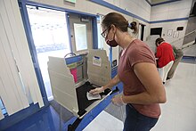 A poll worker sanitizes an election booth in Davis, California Poll worker sanitizes election booth.jpg