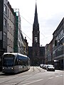 Blick auf die Front der Saarbrücker Johanneskirche, im Vordergrund ein Zug der Saarbrücker Stadtbahn (Wagen 1026) auf der Linie 1 Richtung Siedlerheim