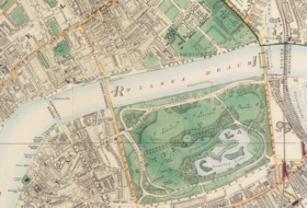 Map of a wide river running east and west through a city. The center is dominated by a green park, mostly south of the river. Four bridges cross the river: two at the park's boundaries, one west of the park, and the other (a railway bridge) east of the park.