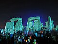 People milling around the floodlit stones