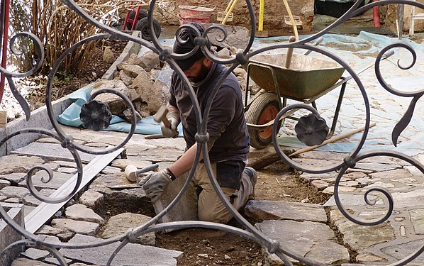 Stonemason cutting stones to size for paving a courtyard in Ticino, Switzerland