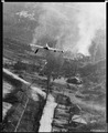 ‏מטוס F-80 מטיל פצצת נפלם על מרכז לוגיסטי בקוריאה הצפונית, בנוסף על המטוס ופצצת נפלם ניתן לזהות פגז המותיר אחריו שובל עשן העולה מתותח נ"מ מוסתר, מאי 1952.
