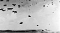 Hornet (lower right) under attack and burning, October 26, 1942. Anti-aircraft shell bursts are visible in the sky over the carrier.