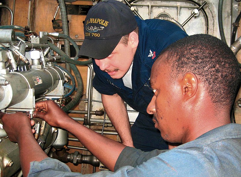 Fichier:US Navy 071116-N-0000X-001 Machinist's Mate 2nd Class Luke Vontagen, a diesel technician assigned to USS Annapolis (SSN 760), works with a Cape Verdean Coast Guardsman to repair a propulsion engine.jpg