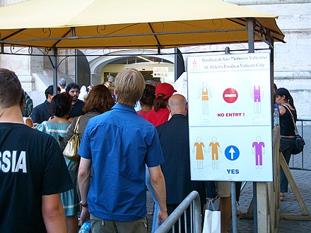 A placard informs tourists about the minimum dress standards required to enter St. Peter's Basilica in Vatican