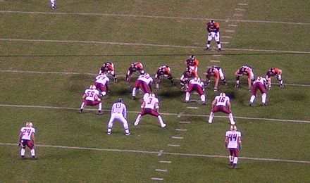 This defense (in white) is in a base 4–3 set. Just behind the four defensive linemen (whose hands are on the ground) are three linebackers (Nos. 55, 3 and 16), and further back are two safeties (numbers 24 and 44).