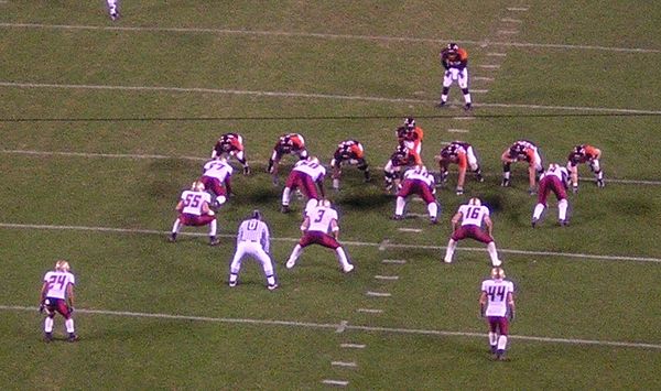 This defense (in white) is in a base 4–3 set. Just behind the four defensive linemen (whose hands are on the ground) are three linebackers (Nos. 55, 3