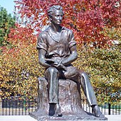 A statue of young Lincoln sitting on a stump, holding a book open on his lap