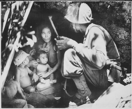 A Marine finds a woman and her four children hiding in a hillside cave. 21 June 1944