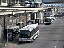 City buses next to an elevated rapid transit station