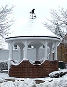 A gazebo during winter, topped with a weather vane