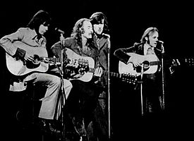The band seated and performing onstage