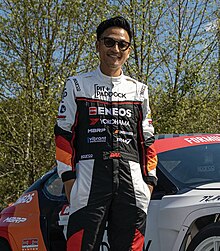 Colour photo of Dai Yoshihara smiling widely and wearing his racing gear