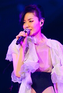 A female in white clothing is singing into a microphone