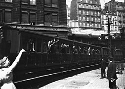 Photo noir et blanc d'un train avec soldats aux fenêtres et femme agitant la main.