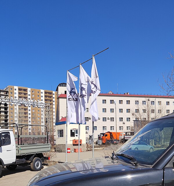 Horizontal flags featuring the GAZelle logo near a GAZelle car shop in Astana