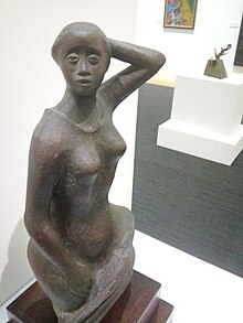 Blick von oben auf eine dunkle Bronzeskulptur von Elizabeth Catlett in einer Ausstellung aus dem Jahr 2016, in der eine unbekleidete Frau dargestellt wird