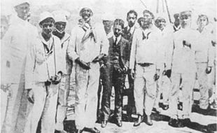 The leader of the Revolt of the Lash, Joao Candido Felisberto (front row, directly to the left of the man in the dark suit), with reporters, police officers and sailors on board Minas Geraes on 26 November 1910. Joao Candido.jpg