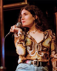 Kate Berlant holding a microphone onstage