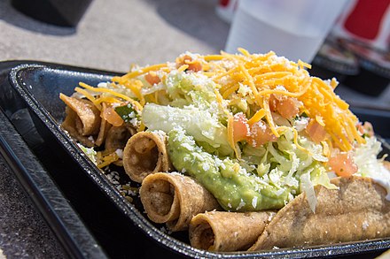 Rolled tacos topped with guacamole and shredded cheese — a San Diego specialty