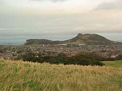 Pohled na Arthur's Seat a Salisbury Crags z Blackford Hill, v pozadí zátoka Firth of Forth