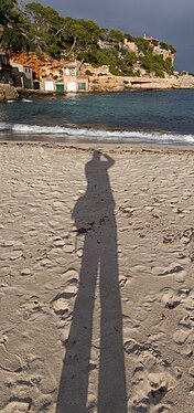 Shadow of the photographer at the bathing beach in the bay Cala Llombards