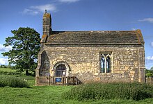 A small chapel-like church seen from the south, with a bellcote at the left, a door and a single window