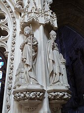 Photo montrant deux statues de saints évêques en pierre blanche sur les montants d'un tombeau monumental