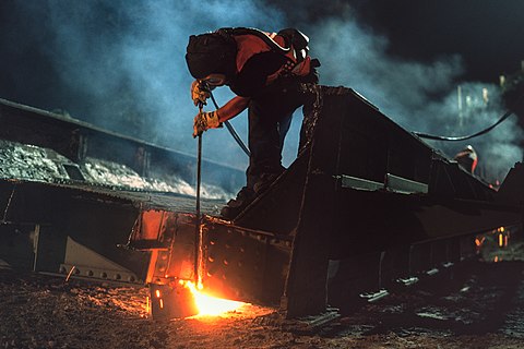 Worker is oxyacetylene cutting to scrap an old railway bridge from 1912 in Leipzig, July 2020 (Kodak Ektachrome E100).