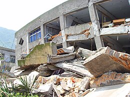 Une structure effondrée au bulldozer, avec une face de montagne exposée en arrière-plan