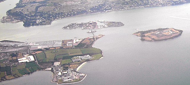 Spike Island (right) is to the southeast of Haulbowline island (middle rearground) and south of Great Island (rearground) within lower Cork Harbour