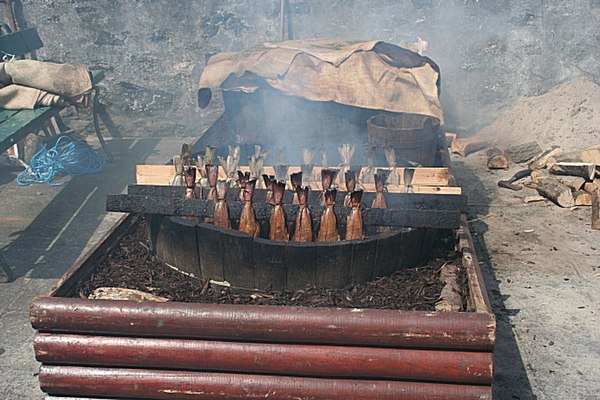 Racks of haddock in a homemade smoker. Smouldering at the bottom are hardwood wood chips. The sacking at the back is used to cover the racks while they are smoked.