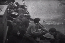 Feature film re-enactment of a British fisherman giving a hand to an Allied soldier while a Stuka's bomb explodes a few metres ahead