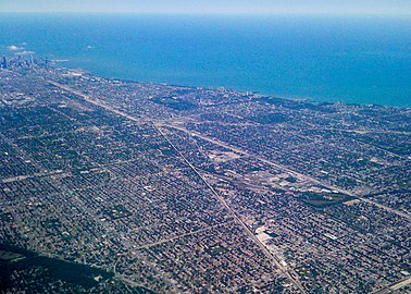 Photographie aérienne montrant une ville située sur un littoral lacustre et composée essentiellement de lotissements individuels.