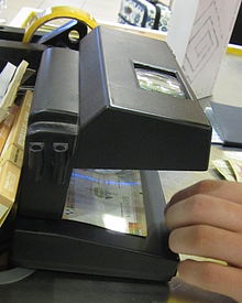 Bill inspection device in use in Peru, showing magnifying glass for inspection of detail and lit up security strip Currency inspection machine - Lima airport (detail).jpeg