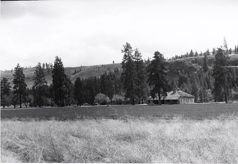 File:Fort Spokane guardhouse. Taken c. 1960. IMAGE DESCRIPTION- Black and white photograph of a field, trees, and a building. In the (55aea067-bd11-4f48-bfb4-b6b9d56d4710).jpg