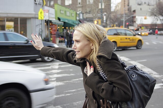 A woman hailing a cab is sending a signal of availability to be picked up.