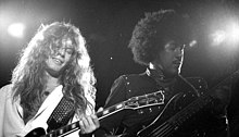 Sykes (left) and Phil Lynott (right) performing with Thin Lizzy at the 1983 Reading Festival. John Sykes with Phil Lynott Thin Lizzie.jpg