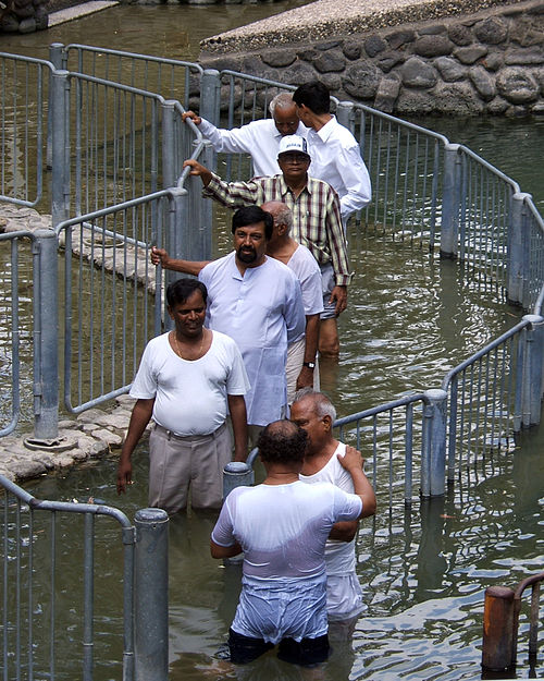 Men lined up to be baptized by immersion in the River Jordan